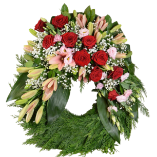 En blomsterkrans med röda rosor, rosa liljor och gröna blad, dekorerad med vita små blommor.